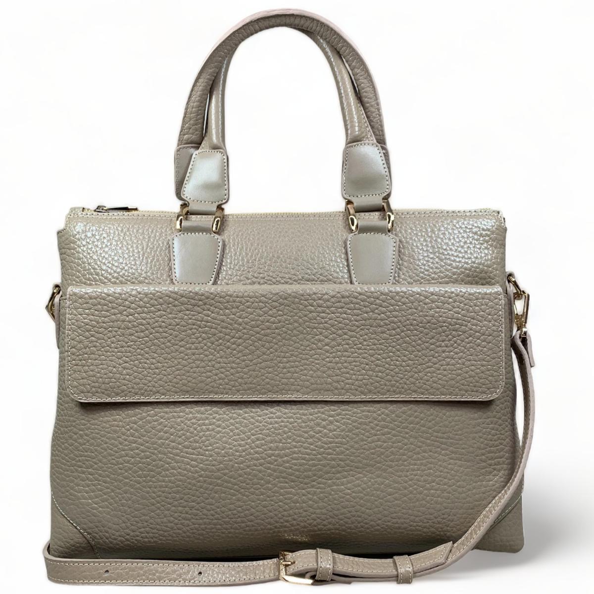 Cream leather laptop bag styled in professional setting demonstrating its business-appropriate design