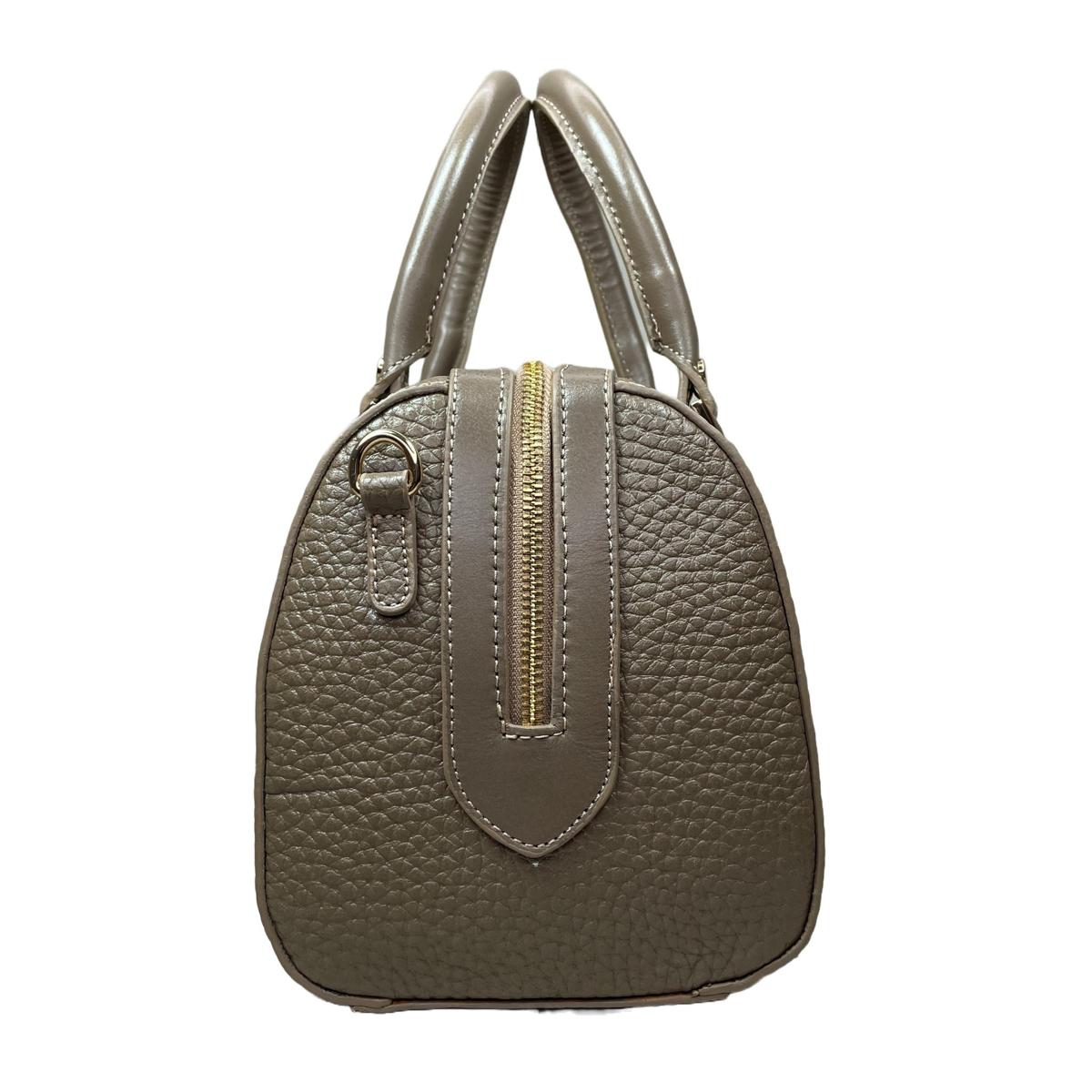 Side view highlighting rounded silhouette and base feet, beige barrel bag