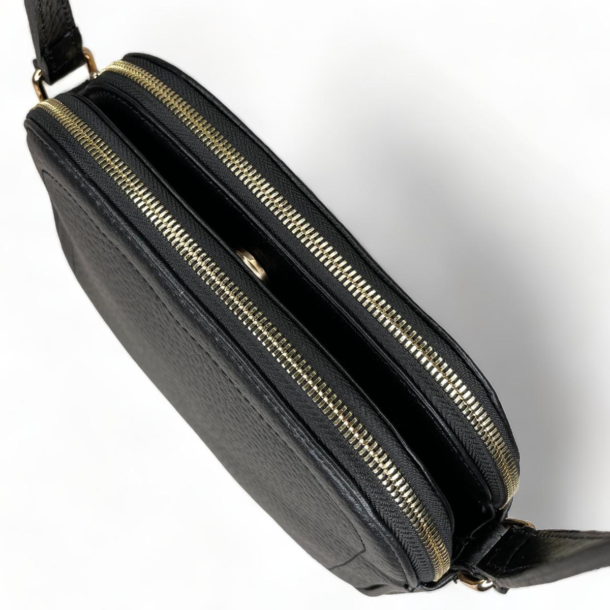 Zipper closure detail on black leather crossbody bag - secure compartment access