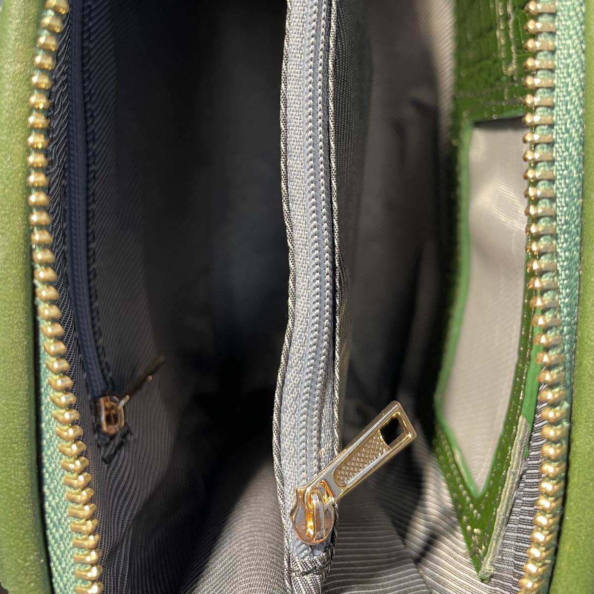 Close-up of green leather clutch interior showing zip compartments and card pockets