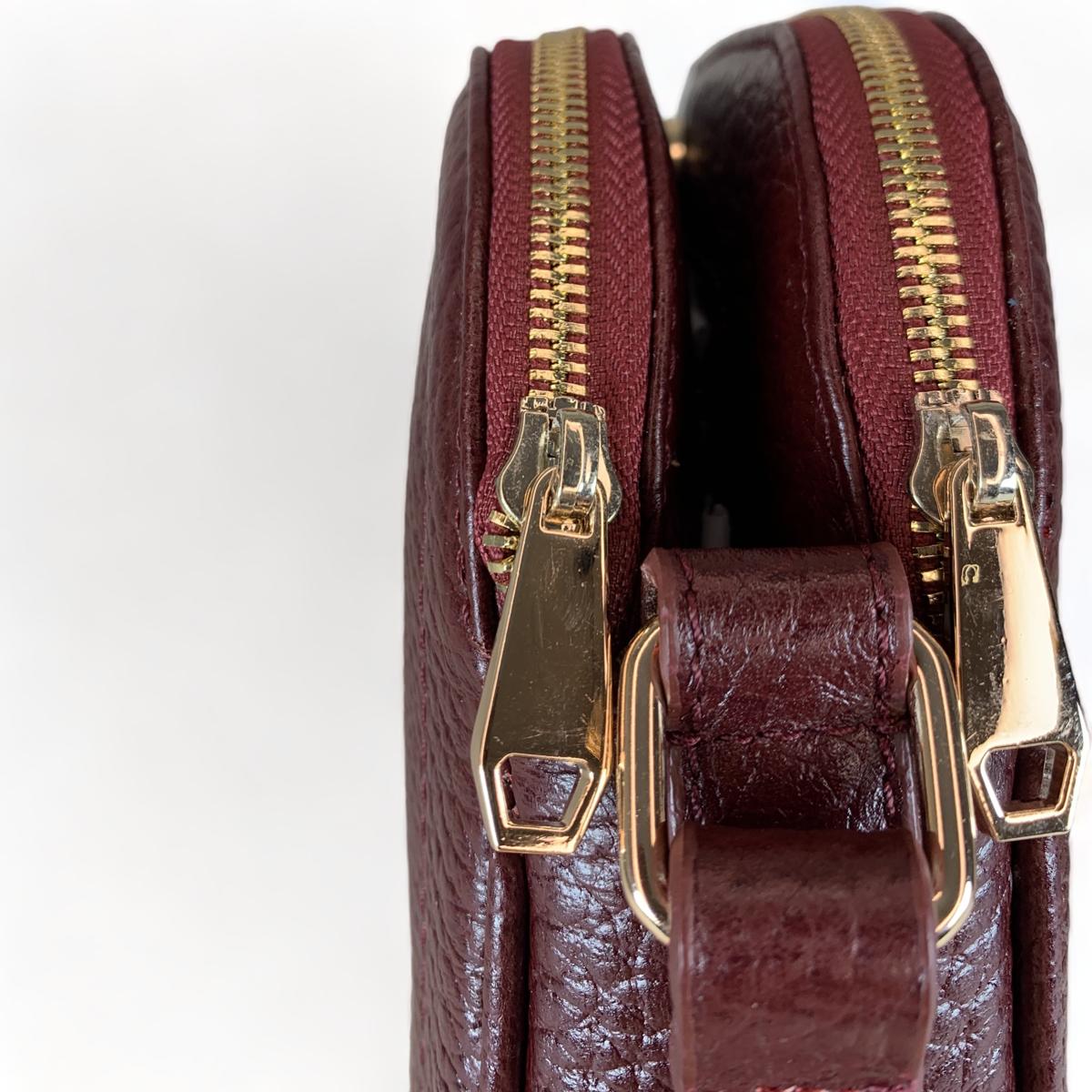 Close-up of red leather grain and hardware on the small women’s shoulder satchel