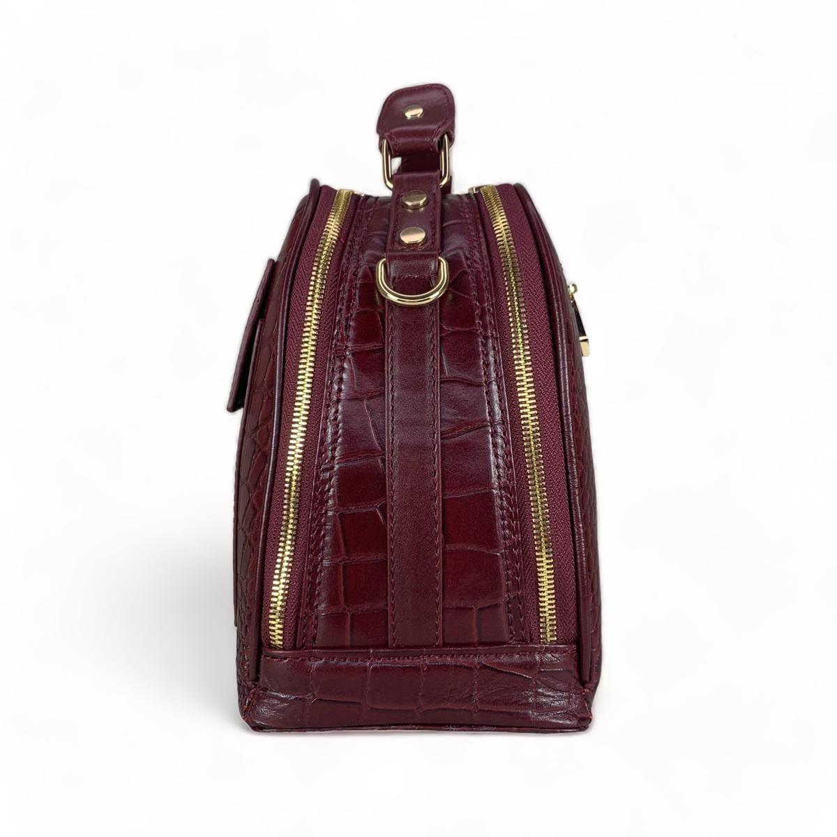 Red leather handbag side profile displaying shoulder strap and compartments