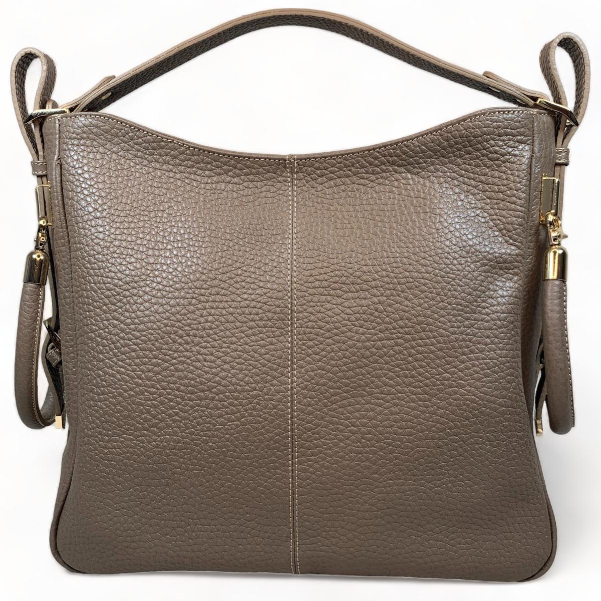 Close-up of woman holding beige leather tote bag - showcasing elegant design and craftsmanship