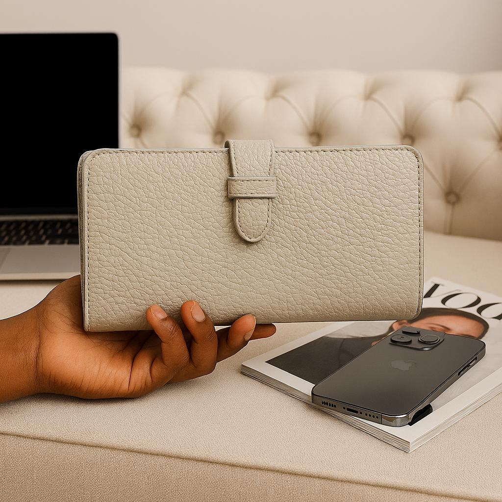 Lifestyle: cream leather clutch held in hand beside phone and magazine