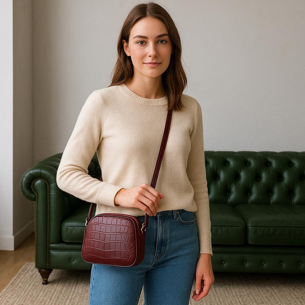 Woman holding a maroon handbag in a room with a green couch.