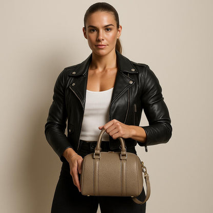 Woman holding a beige handbag against a plain background