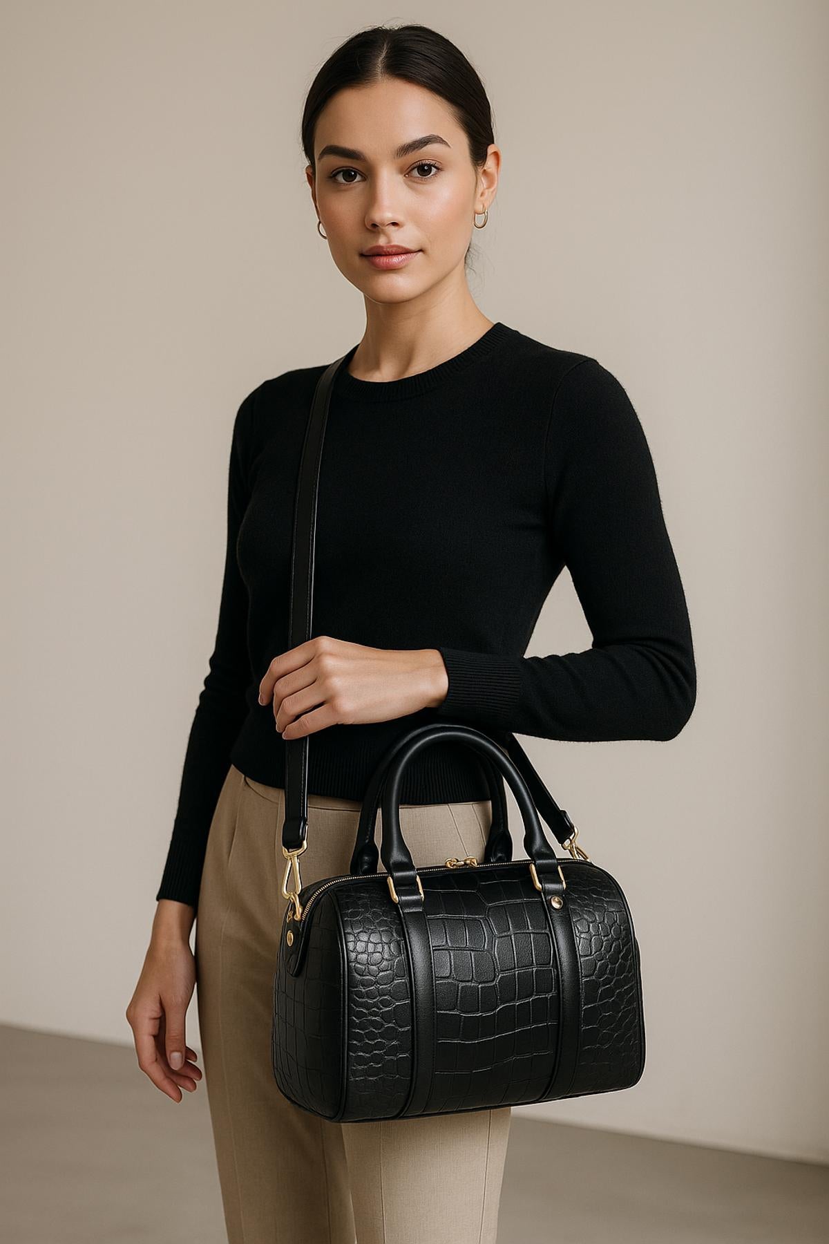 Woman holding a black handbag against a neutral background