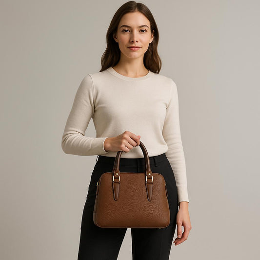 Woman holding a brown handbag against a plain background