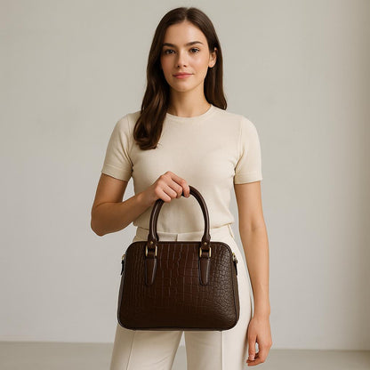Woman holding a brown handbag against a plain background