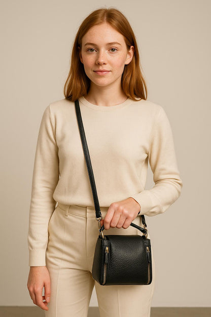 Woman holding a black handbag against a neutral background