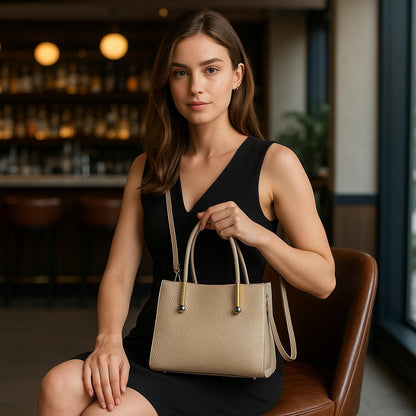 Woman holding a beige handbag in an indoor setting