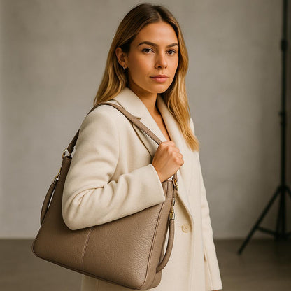 Woman holding a beige handbag against a neutral background