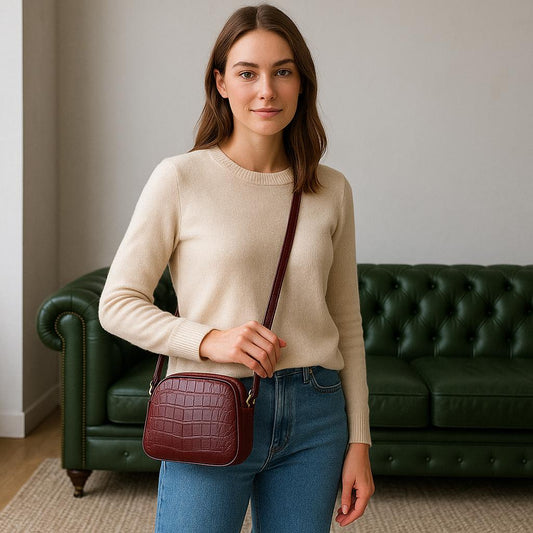 Woman holding a maroon handbag in a room with a green couch.