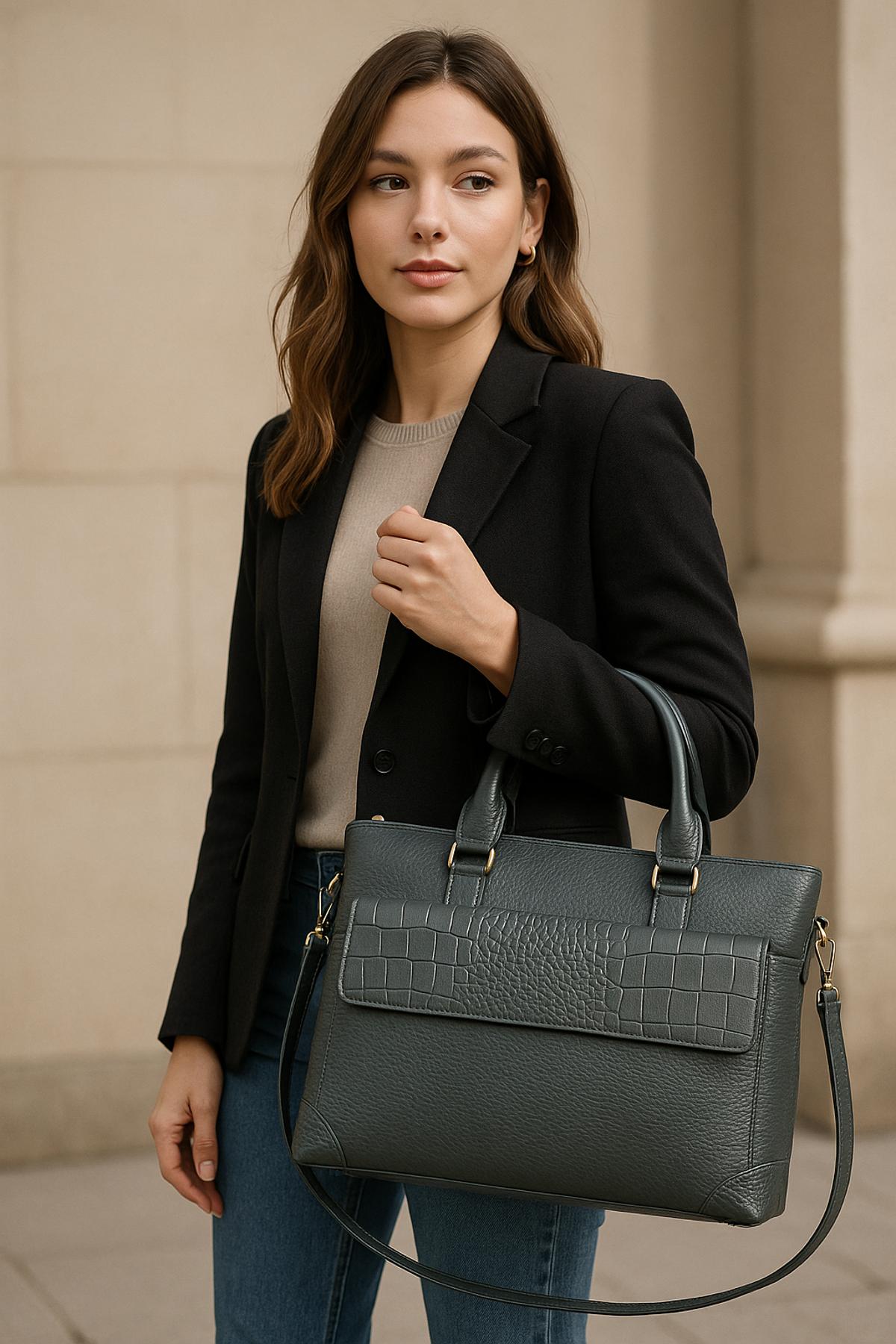 Woman holding a dark gray handbag against a neutral background.